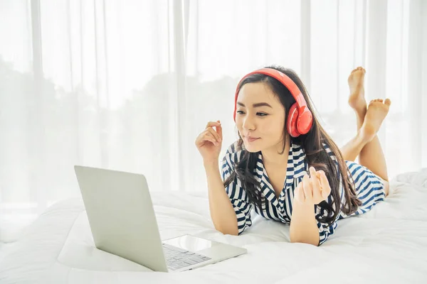 Молодая Женщина Расслабляется Слушает Музыку Используя Ноутбук Кровати Спальне Копировальным — стоковое фото