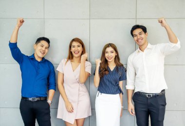 İş kazananlar. Takımına güveniyor. Bir grup mutlu genç kutlama yapıyor, el kol hareketi yapıyor, kollarını havada tutuyor ve pozitifliklerini dile getiriyorlar..