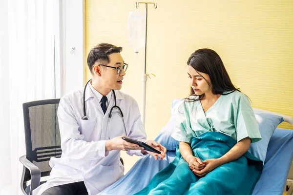 아시아 의사는 침대에서 아시아 환자와 이야기하면서 결과를 선택적 점에서 환자에게 — 스톡 사진
