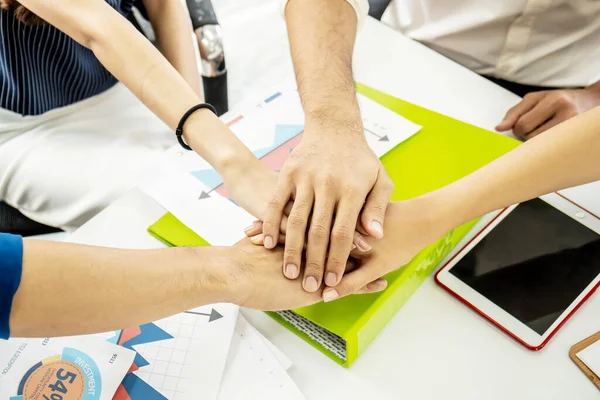 Business Team Stack Hands Support Concept. Four business people in formal wear sitting and discussing and shake hands and folding their hands on hands of success concept Symbol of cooperation