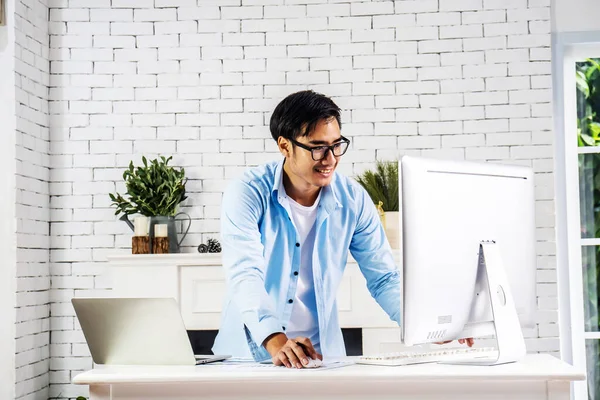 Young smiling happy asian man relaxing connected on internet with laptop computer working and video conference meeting at home.Young creative typing on keyboard.work from home