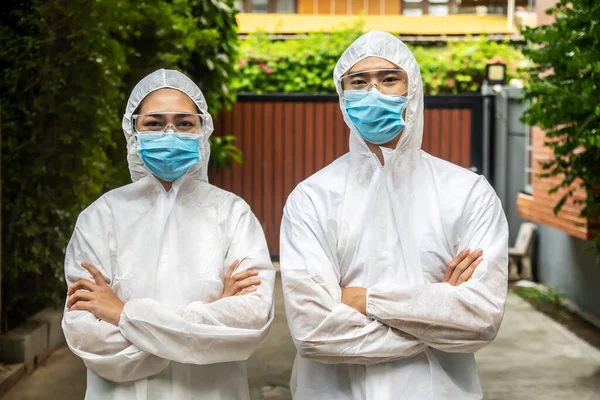 Asyalı doktor erkek ve hemşire kadın PPE giysisi ya da kişisel koruyucu ekipman ve tıbbi maske giyer. Bu maske evde güvenlik amaçlı ziyaret eden virüs salgını hastalarını korur.