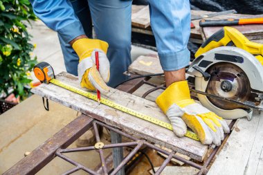 İnşaat işçisi, tahta ve kalemi ölçmek için mezura kullanıyor. Erkek ellerinin ahşap döşemeyi, inşaat endüstrisini, ev işlerini kendin yap..