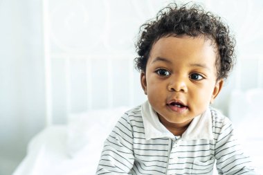 Yatağın üzerinde pofuduk saçlı sevimli Afrikalı bebek, tatlı çocuk.