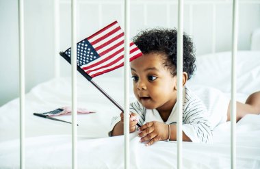 Afro-amerikan bebek Amerikan bayrağını yatakta tutuyor.