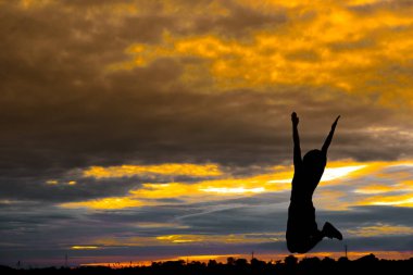 Formda kadın silueti gün batımında yoga yapıyor.