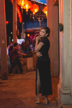 Siyah elbiseli Asyalı bir kadının portresi şehir merkezindeki caddede bir kızın tarzını kapatıyor.