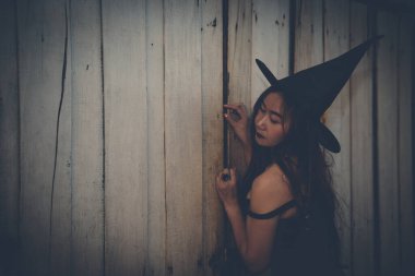 Asyalı güzel kadın Cadı Şapkalı siyah bir elbise giyiyor, Cadılar Bayramı konsepti.