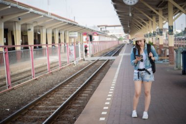 Asyalı turist tren istasyonunda bekler, Taylandlı hippi gezmeye gider.