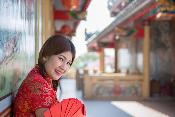 Portrait of beautiful asian woman in Cheongsam dress with Red envelope in hand,Thailand people,Happy Chinese new year concept