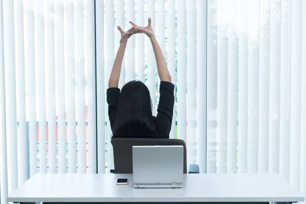 Asian officer woman stretching body at the desk of office from back angle,Thailand people,Businesswoman tired from hard work