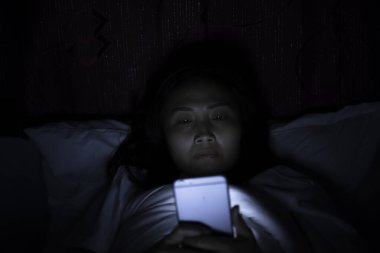 Asyalı kadın gece yatakta akıllı telefon çalar, Taylandlılar...