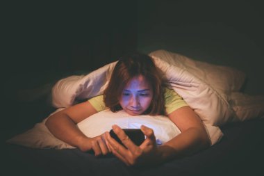 Asyalı kadın gece yatakta akıllı telefon oynuyor, Taylandlılar, sosyal medya bağımlısı, bütün gece internet oynuyor.