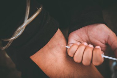 Asyalı adam siyah başlıklı umutsuz uyuşturucu bağımlısı, aşırı dozda uyuşturucu bağımlısı ve bilinç kaybı uyuşturucu ölüme, Taylandlılara, kan damarlarına eroin enjekte etmeye neden oluyor.