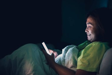 Asyalı kadın gece yatakta akıllı telefon oynuyor, Taylandlılar, sosyal medya bağımlısı, bütün gece internet oynuyor.