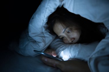 Asyalı kadın gece yatakta akıllı telefon çalar, Taylandlılar...
