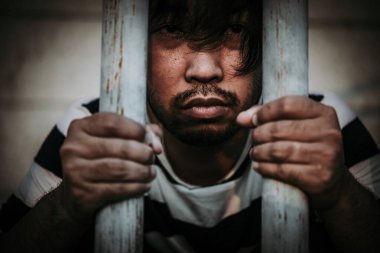 Demir hapishaneyi yakalamak için çırpınan tutuklunun portresi.