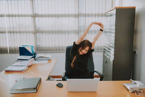 Asian officer woman stretching body at the desk of office