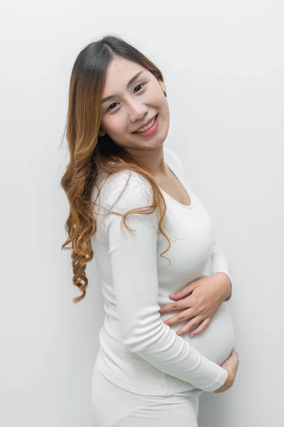 白いドレスの妊婦立ちポーズのために写真を撮る白の背景 — ストック写真