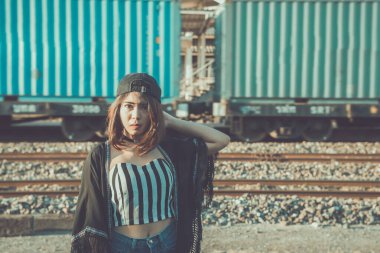 Demiryolunda jant ışığı, yumuşak odak, yaşam tarzı, koyu renk tonu, film tonu, pastel fotograflar, tren geçişi olan genç ve güzel siyah şapkalı hippi kadın.