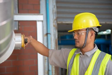 Kazan dairesinde çalışan gözlüklü Asyalı mühendis, ısıtma sistemi ekipmanlarının teknik verilerini kontrol ediyor, Taylandlılar
