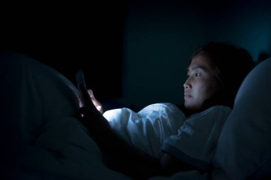 Asyalı kadın gece yatakta akıllı telefon çalar, Taylandlılar...