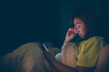 Asyalı kadın gece yatakta akıllı telefon oynuyor, Taylandlılar, sosyal medya bağımlısı, bütün gece internet oynuyor.