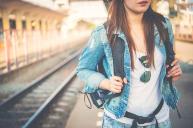 Asyalı turist tren istasyonunda bekliyor. Taylandlı hippi kadın seyahat ediyor. Elinde kamera var.