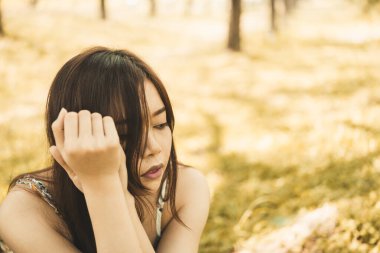 Asyalı üzgün kadının, ağaç mahsulü tarzında, kalp kırıcı kız konseptinin altında oturduğu yakın plan.