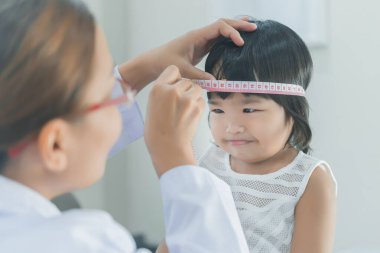 Solunumunu ve kalbini kontrol etmek için steteskop kullanan Asyalı bir doktor, Taylandlı çocukların sağlığını kontrol ediyor.