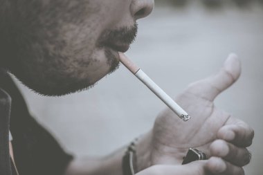 Asyalı adam sigara içmek için çakmak kullanıyor, dünya tütün günü değil.