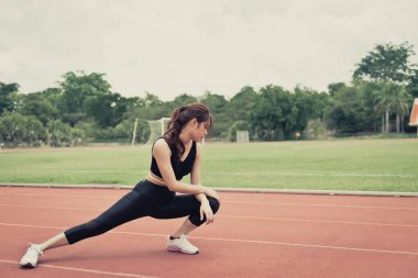 Asyalı zayıf kadın sabah antrenmanından önce ısınıyor, zayıf kız yaşam için egzersiz yapıyor, seçici odaklanma, parlak güneş ışığı, Taylandlılar...