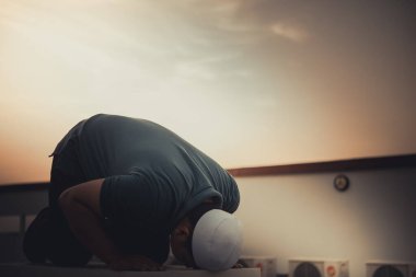 Genç bir Asyalı Müslüman gün batımında dua ediyor, Ramazan festivali konsepti.