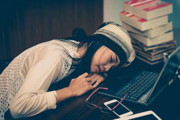 beautiful asian woman sleep on the desk with laptop in the library