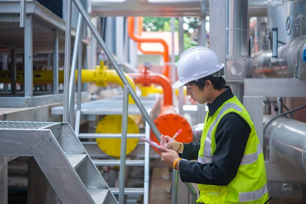 Asian Maintenance engineer at the waste water management system of a huge factory,maintenance checking technical data of heating system equipment,Thailand people