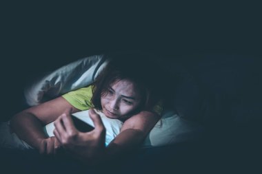 Asyalı kadın gece yatakta akıllı telefon oynuyor, Taylandlılar, sosyal medya bağımlısı, bütün gece internet oynuyor.