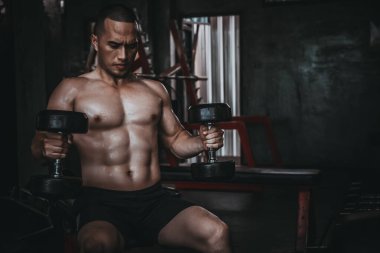 Asyalı bir adamın portresi spor salonundaki büyük kaslar Tayland 'daki insanlar sağlıklı vücut ağırlık çalışması spor salonundaki vücut ağırlığı konsepti, karın kaslarına eşek şakası, çöp çanı kaldırma.