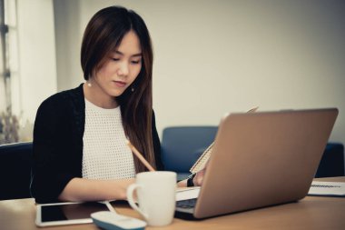 Akşam ofiste çalışan güzel Asyalı kadın Tayland 'lı işçi şirketteki patronla telefonda konuşuyor.