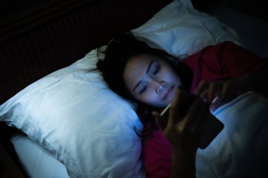 Asyalı kadın gece yatakta akıllı telefonla oyun oynuyor, Taylandlılar, sosyal medya bağımlısı.