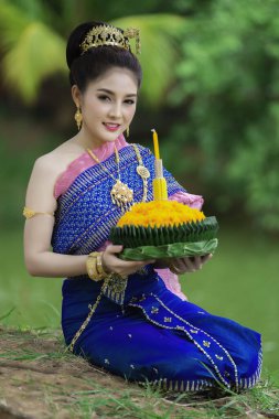 Tayland elbisesi içindeki güzel Asyalı kadın portresi geleneksel dua Kratong 'u, Tayland' da düzenlenen loy kratong festivaline katılması için tutuyor.