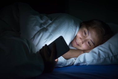 Asyalı kadın gece yatakta akıllı telefon çalar, Taylandlılar...