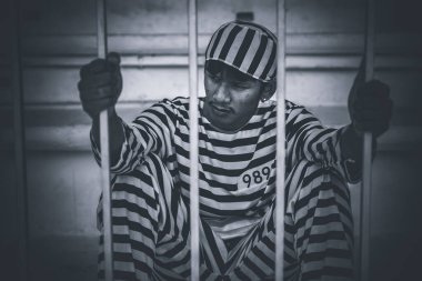 Demir hapishaneyi yakalamak için çırpınan tutuklunun portresi.