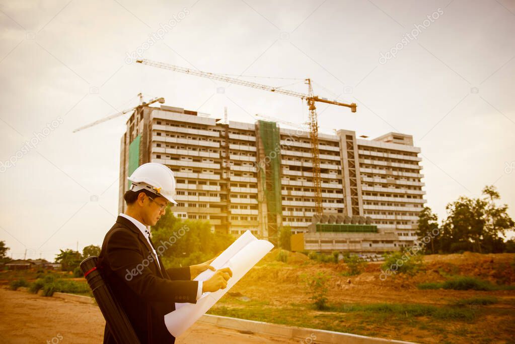 Young asian engineer looking paper plan of the building