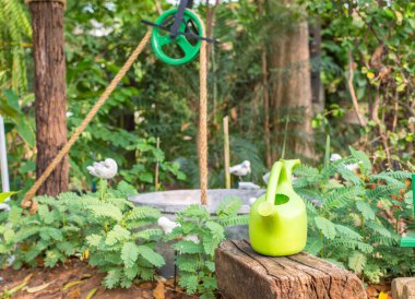 Bahçedeki bankta Green Waterring konservesi. Makara, ağaçlar.