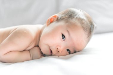 Sevimli Asyalı bebek yatağın ön tarafından uzanıyor.