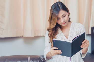 Asyalı hamile kadın evde bir kitap okudu, Taylandlı çocukları nasıl yetiştireceği üzerine.