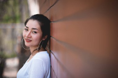 Güzel Asyalı şık kızın portresi tuğla duvarda fotoğraf çektirmek, gençlerin yaşam tarzı, modern kadın mutlu konsepti.