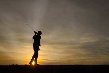 Siluet Asyalı golfçü güzel günbatımında golf oynuyor