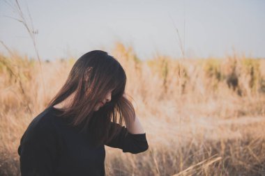 Tarlada yapayalnız bir kadının portresi. Klasik filtre stili. Aşktan kalbi kırık, günbatımı tarzında üzgün kız konsepti.