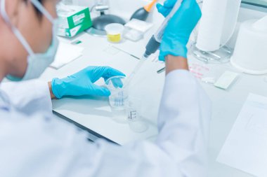 Bilim adamları plastik tüplere kimyasallar enjekte etti. Kucağında çalışan bir Suientist.